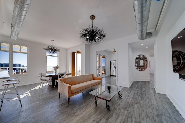 living room featuring an inviting chandelier, baseboards, and wood finished floors