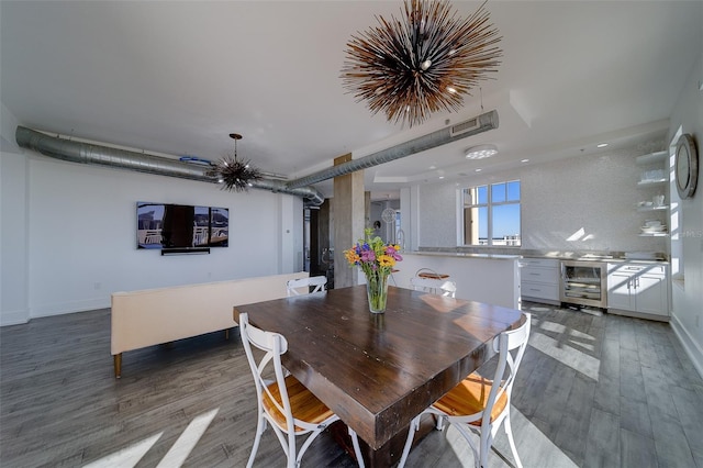 dining area with wine cooler, a notable chandelier, visible vents, wood finished floors, and baseboards