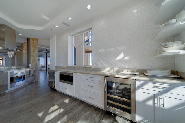 kitchen featuring island exhaust hood, dark wood-type flooring, white cabinets, beverage cooler, and oven