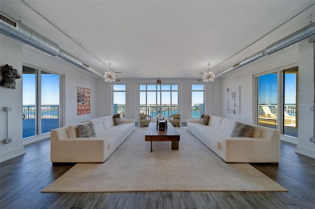 living room featuring baseboards, visible vents, a notable chandelier, and wood finished floors