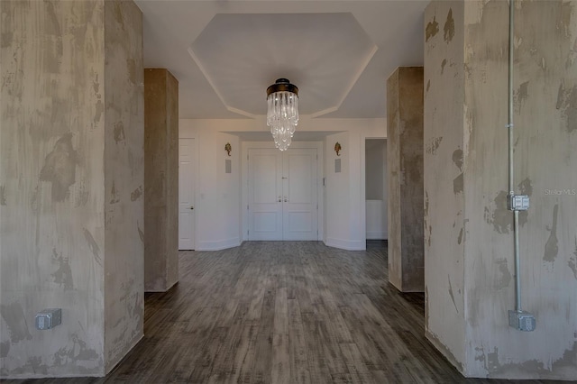 interior space featuring baseboards, wood finished floors, a raised ceiling, and an inviting chandelier