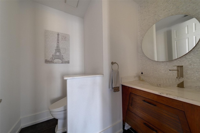 bathroom featuring baseboards, decorative backsplash, toilet, tile patterned flooring, and vanity