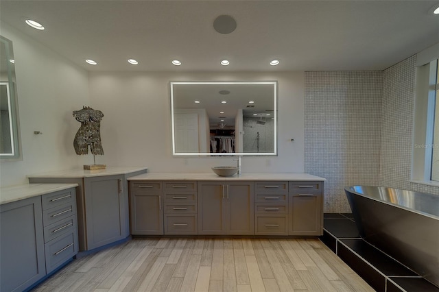 full bathroom with a freestanding tub, wood finished floors, vanity, and recessed lighting