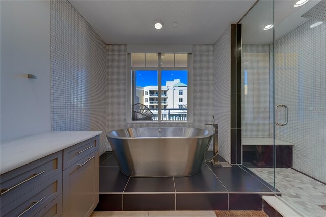 bathroom featuring a freestanding tub, a stall shower, tile patterned flooring, and tile walls