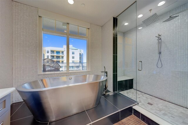 bathroom with a stall shower, a soaking tub, tile walls, and tile patterned floors