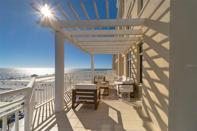 view of patio / terrace featuring a beach view, a balcony, a water view, an outdoor living space, and a pergola