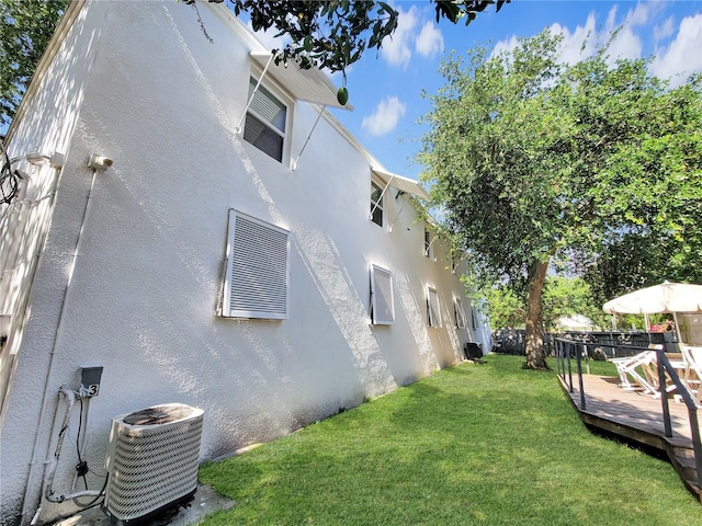 view of side of home featuring central AC unit, a lawn, and a deck