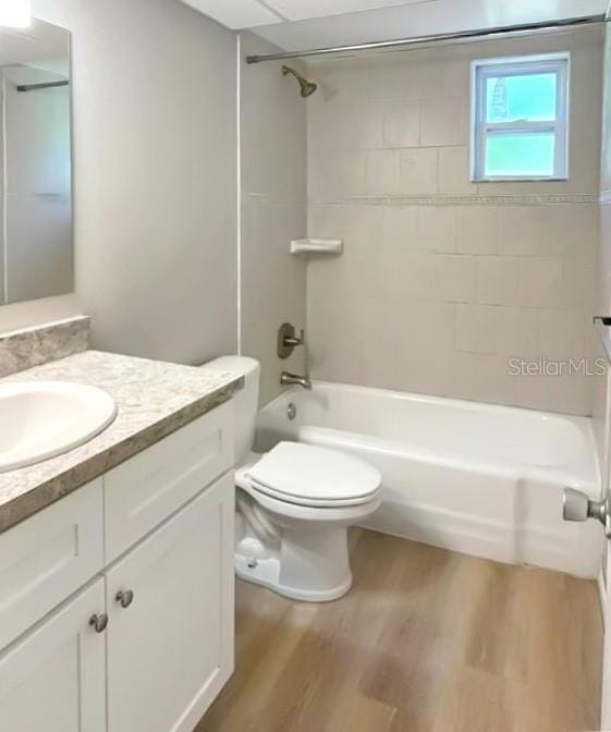 full bathroom with vanity, toilet, tiled shower / bath combo, and hardwood / wood-style floors