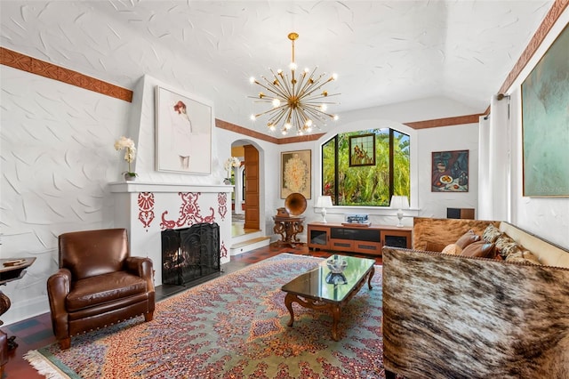 living room featuring a tiled fireplace, vaulted ceiling, hardwood / wood-style floors, and a notable chandelier