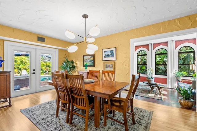 dining room with french doors, an inviting chandelier, and light hardwood / wood-style flooring