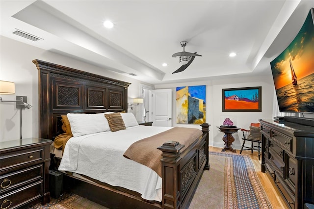 bedroom featuring light hardwood / wood-style flooring and a tray ceiling