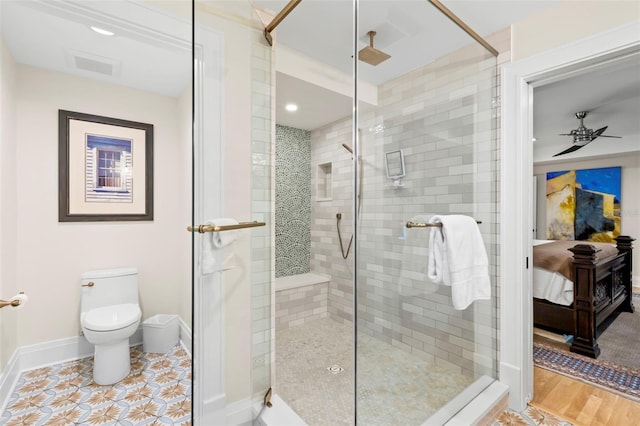 bathroom with ceiling fan, a shower with shower door, and toilet