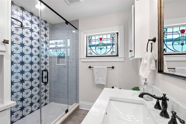 bathroom with tile patterned floors, plenty of natural light, an enclosed shower, and vanity