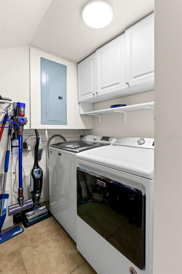 clothes washing area with electric panel, cabinets, washer and dryer, a textured ceiling, and light tile patterned flooring