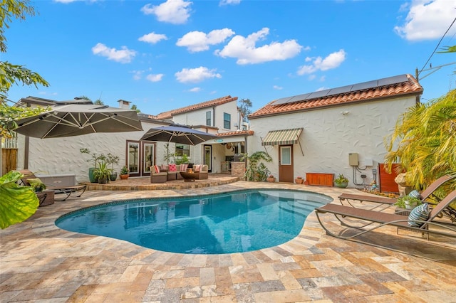 rear view of property with an outdoor living space, a patio, and solar panels