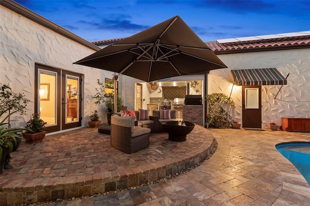 patio terrace at dusk with area for grilling and french doors