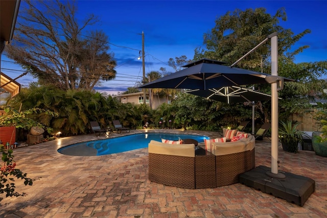 pool at dusk featuring an outdoor living space and a patio