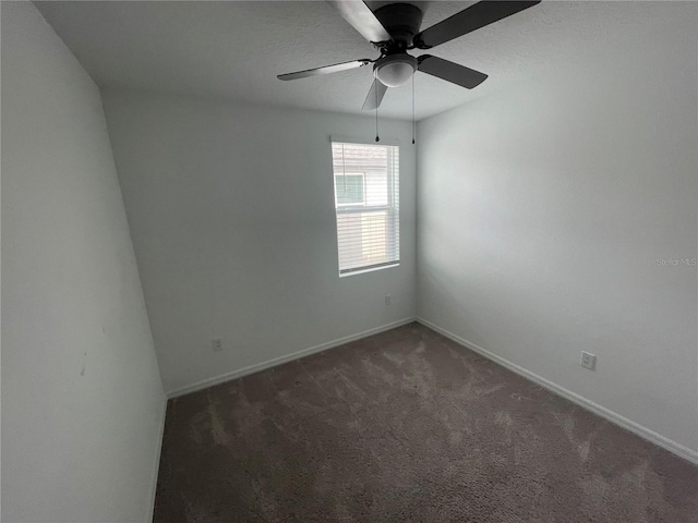 empty room featuring ceiling fan and dark carpet