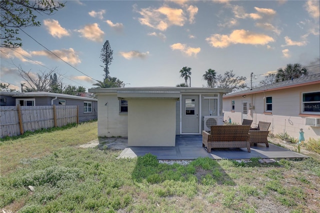 rear view of house with ac unit, a lawn, and outdoor lounge area