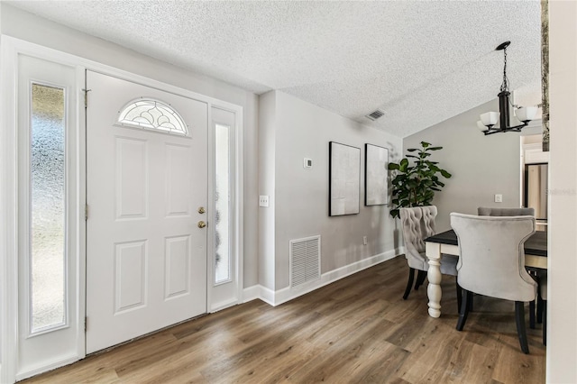 entrance foyer featuring hardwood / wood-style flooring, plenty of natural light, a textured ceiling, and a chandelier