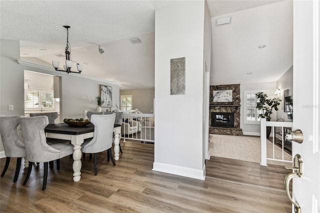 dining space featuring lofted ceiling, a fireplace, wood-type flooring, and a wealth of natural light