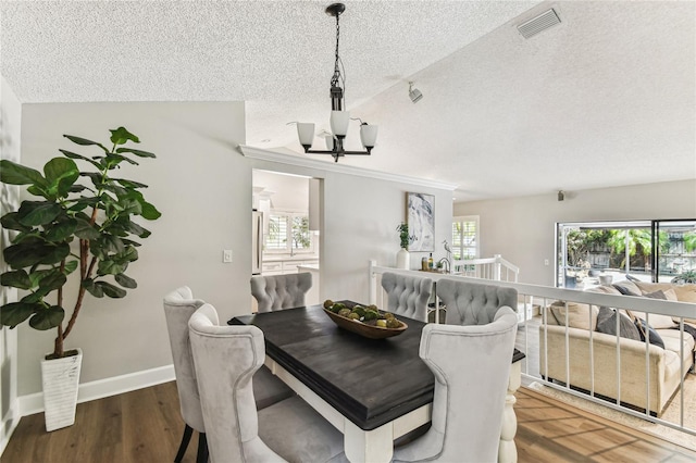 dining area featuring dark wood-type flooring, a healthy amount of sunlight, and a textured ceiling