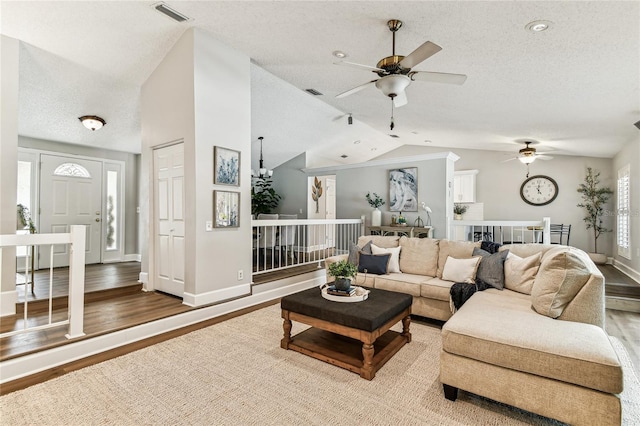 living room with ceiling fan, hardwood / wood-style flooring, vaulted ceiling, and a textured ceiling