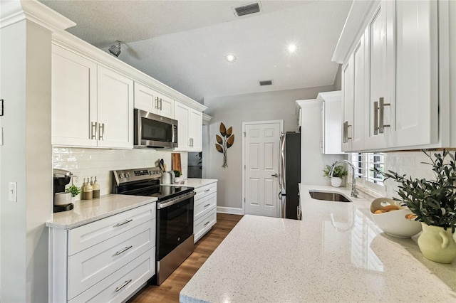 kitchen with sink, appliances with stainless steel finishes, white cabinetry, tasteful backsplash, and light stone countertops