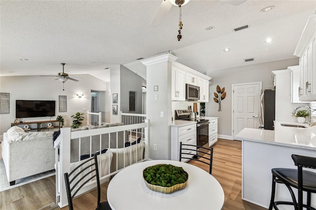 kitchen featuring lofted ceiling, sink, ceiling fan, stainless steel appliances, and white cabinets