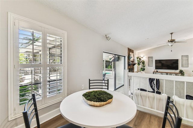 dining area with hardwood / wood-style flooring, vaulted ceiling, and a textured ceiling