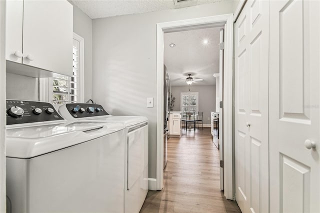 laundry room with cabinets, a textured ceiling, independent washer and dryer, and light hardwood / wood-style floors