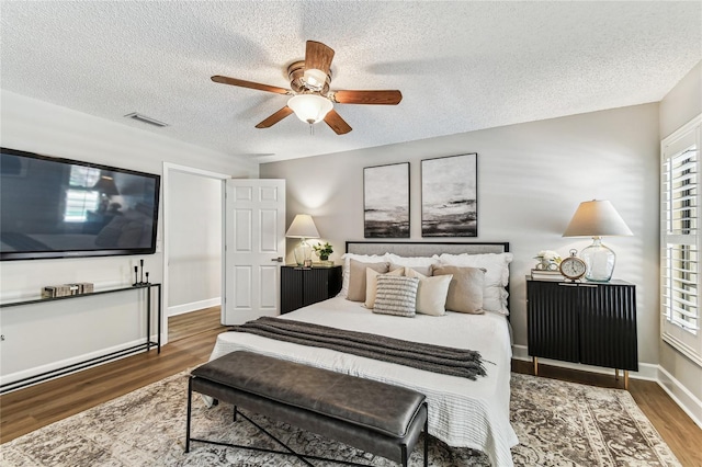 bedroom featuring ceiling fan, dark wood-type flooring, and a textured ceiling