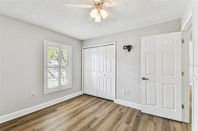 unfurnished bedroom with hardwood / wood-style floors, a closet, a textured ceiling, and ceiling fan