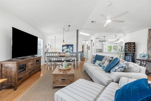 living room featuring vaulted ceiling, ceiling fan, a healthy amount of sunlight, and light hardwood / wood-style floors