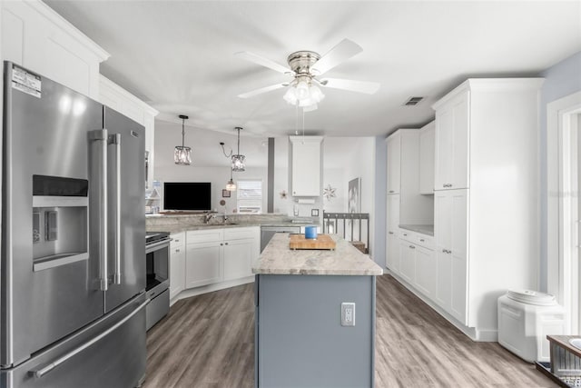 kitchen featuring white cabinetry, hanging light fixtures, stainless steel appliances, a kitchen island, and kitchen peninsula