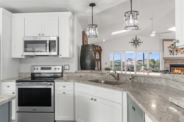 kitchen with sink, appliances with stainless steel finishes, white cabinetry, light stone counters, and decorative light fixtures