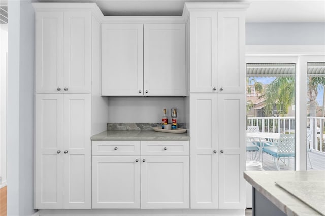 bar with white cabinets and light stone counters