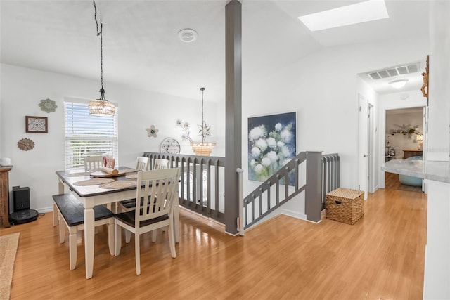 dining room featuring a skylight, a chandelier, and light wood-type flooring