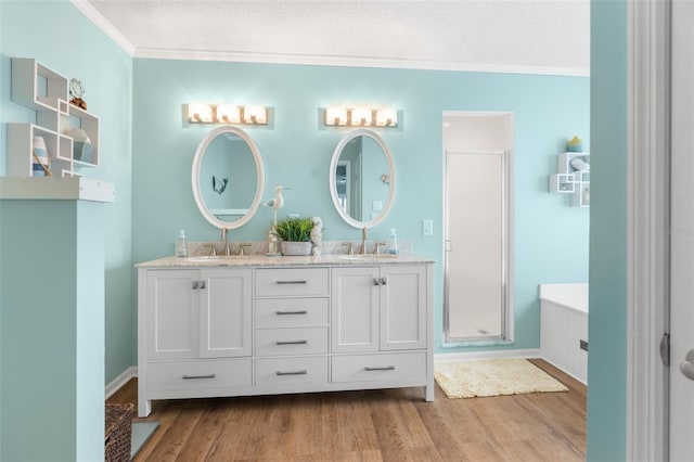 bathroom with hardwood / wood-style flooring, ornamental molding, vanity, a shower with door, and a textured ceiling