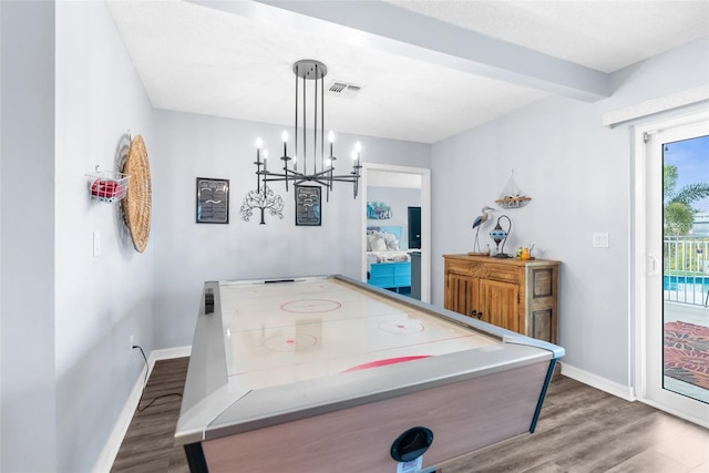 recreation room featuring dark wood-type flooring, an inviting chandelier, and beam ceiling