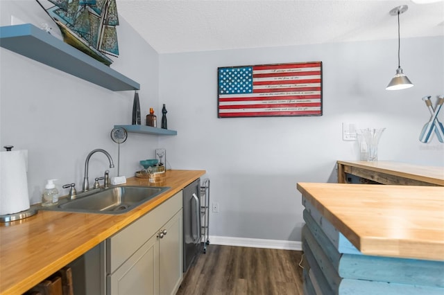 kitchen with sink, butcher block countertops, a textured ceiling, dark hardwood / wood-style floors, and pendant lighting