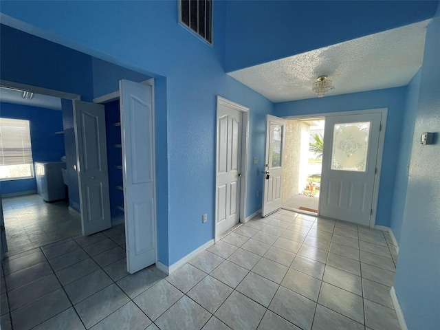 entrance foyer with a healthy amount of sunlight, light tile patterned floors, and a textured ceiling