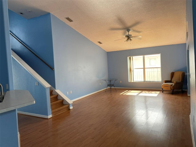 unfurnished living room featuring wood-type flooring, lofted ceiling, a textured ceiling, and ceiling fan