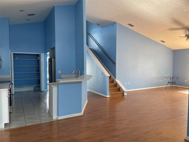 kitchen featuring a textured ceiling, wood-type flooring, fridge, and ceiling fan