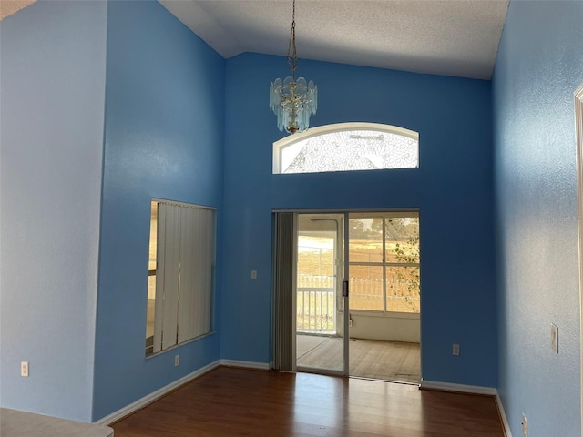 foyer featuring wood-type flooring, high vaulted ceiling, a textured ceiling, and an inviting chandelier