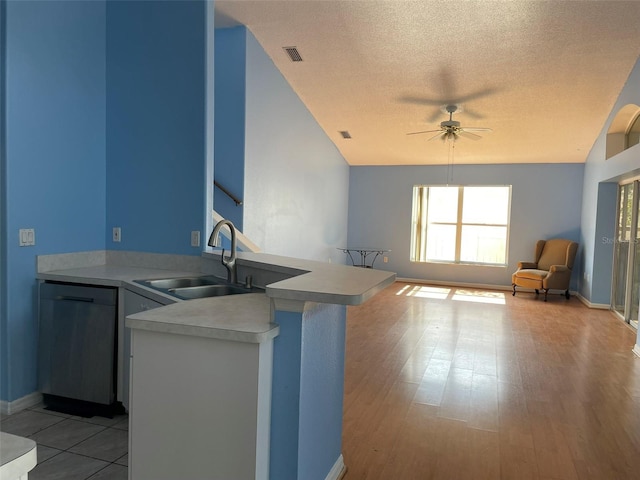 kitchen with sink, a breakfast bar area, ceiling fan, a textured ceiling, and kitchen peninsula