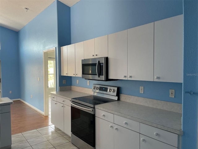 kitchen with white cabinetry, stainless steel appliances, and light tile patterned flooring