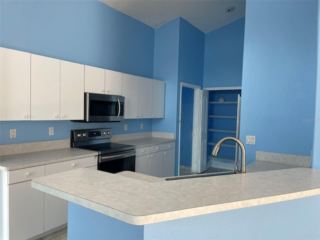 kitchen with white cabinetry, sink, a towering ceiling, and stainless steel appliances