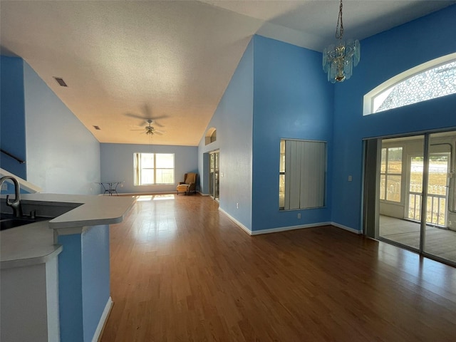 unfurnished living room with ceiling fan with notable chandelier, dark hardwood / wood-style flooring, sink, and a textured ceiling