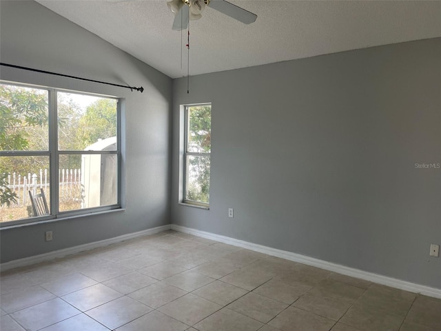 tiled empty room with ceiling fan, lofted ceiling, and a textured ceiling